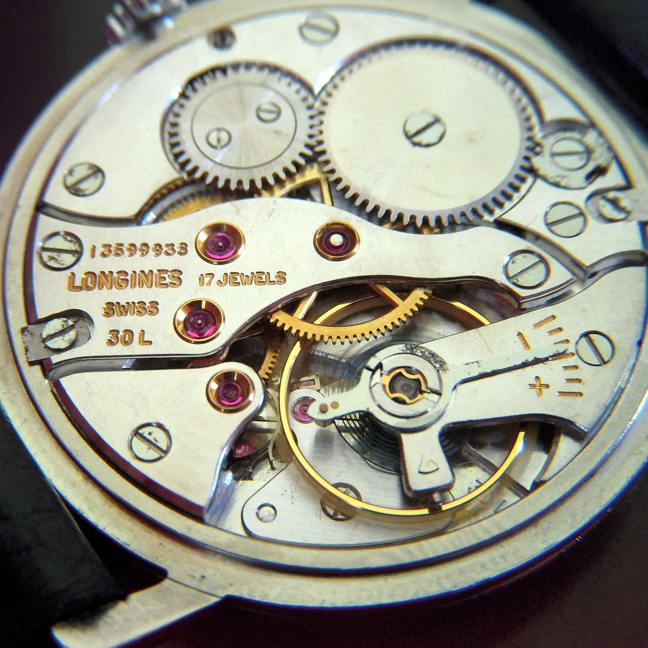 Longines mechanical movement with gears and jewels Close-up view of a mechanical watch movement showing gears, screws, and text indicating "Longines 17 Jewels Swiss 30L.