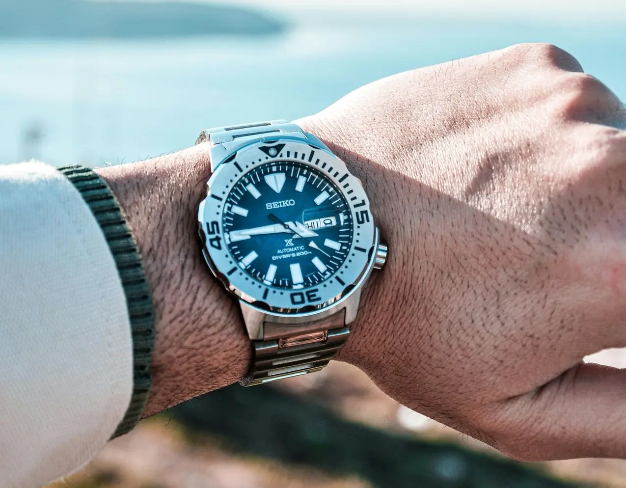A Seiko automatic diving watch on a wrist, with a blue dial, bold white markers, and a stainless steel bezel and bracelet.