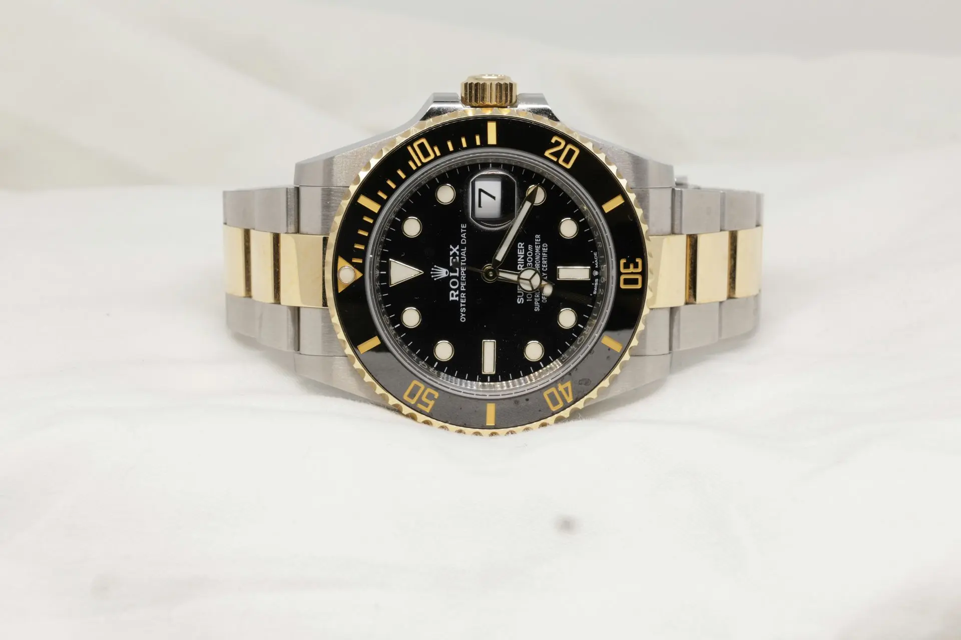 Two-Tone Rolex Submariner Style Watch wo-tone Rolex Submariner-style wristwatch with a black dial, gold bezel, and stainless steel and gold bracelet on a light surface.
