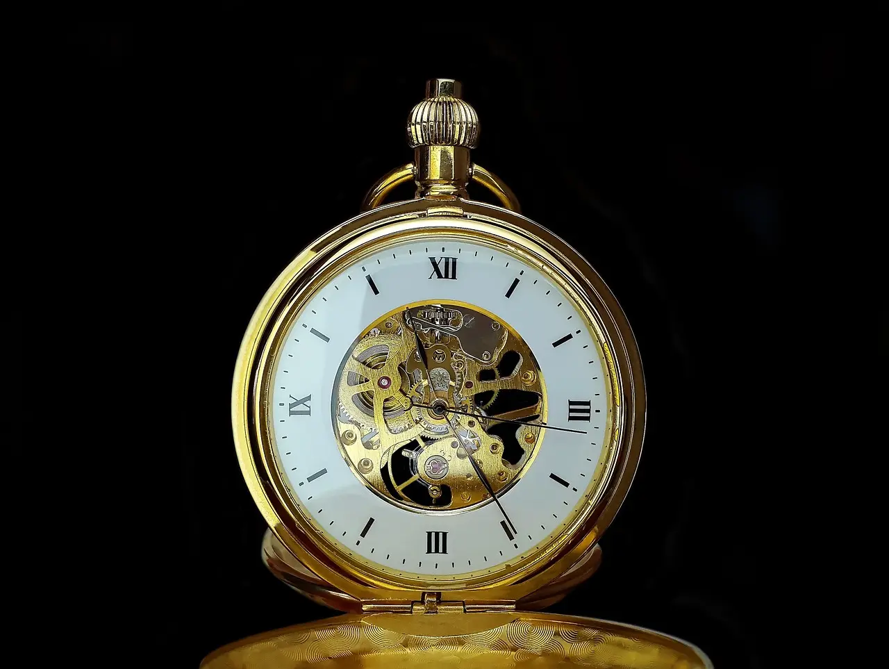 old Pocket Watch with Skeleton Movement Gold-tone pocket watch with a white dial showing Roman numerals and a visible mechanical movement through a skeleton center, set against a dark background.