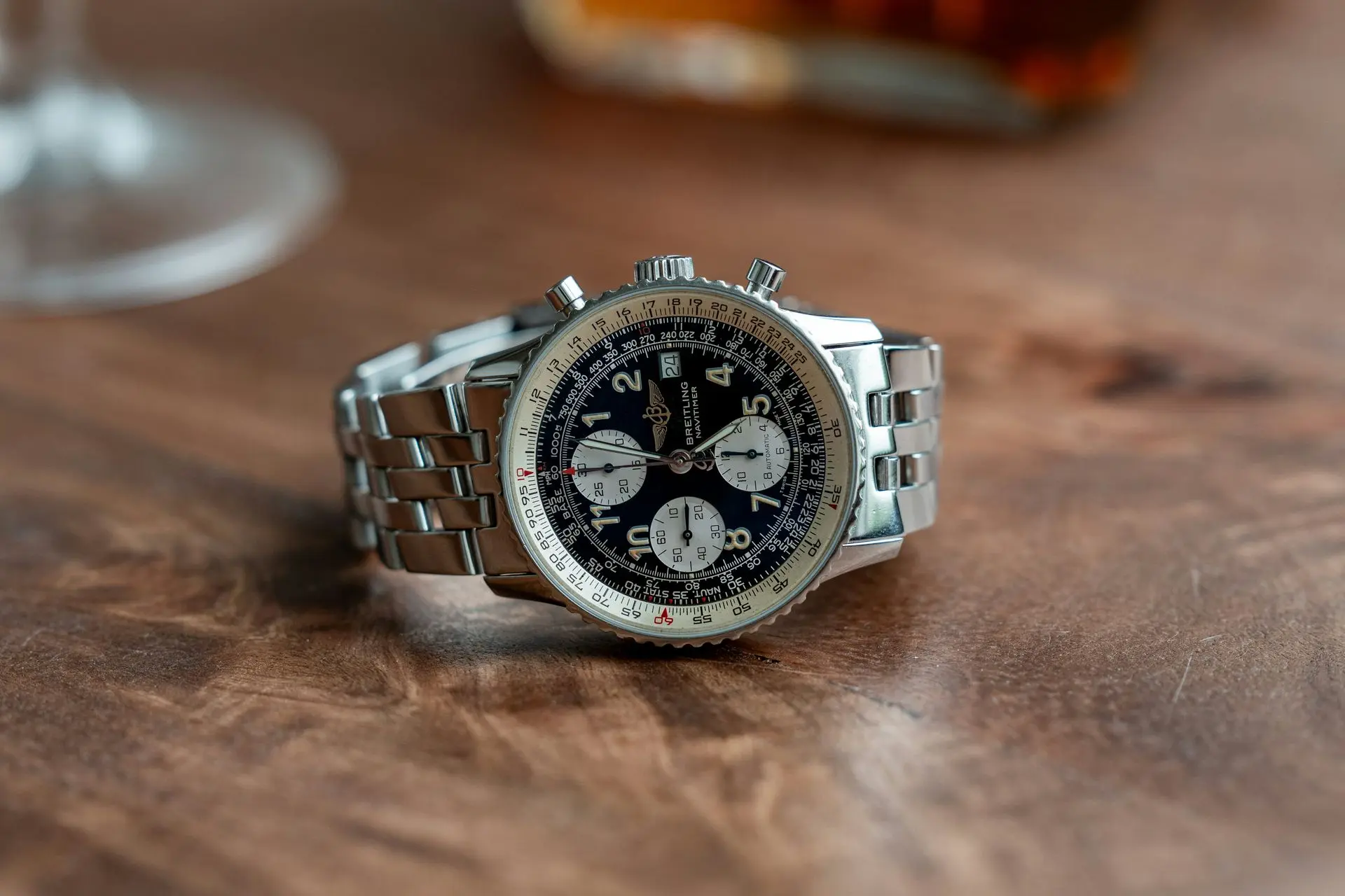 A close-up image of a Breitling Navitimer chronograph watch with a black dial, stainless steel case and bracelet, and multiple subdials.