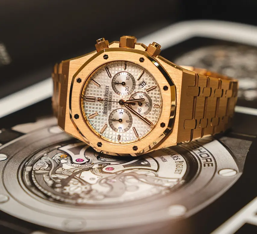 Audemars Piguet Royal Oak gold-toned chronograph wristwatch with a textured silver dial, multiple sub-dials, and a integrated link bracelet, resting on a display surface.