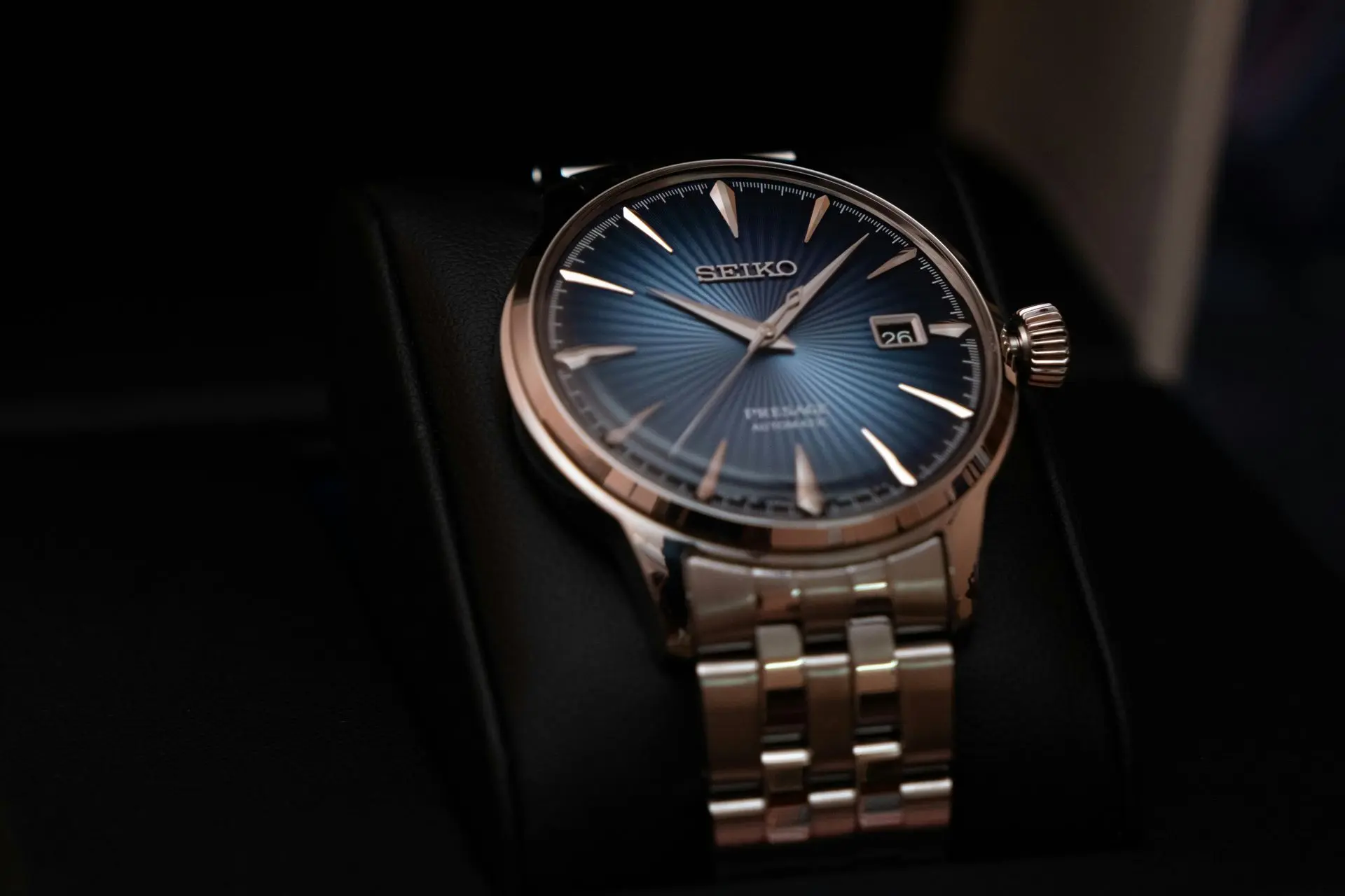 Seiko Presage Cocktail Time “Ladies Edition” A Seiko wristwatch with a blue sunburst dial, silver hour markers, date display, and a metal link bracelet, displayed on a black watch cushion.