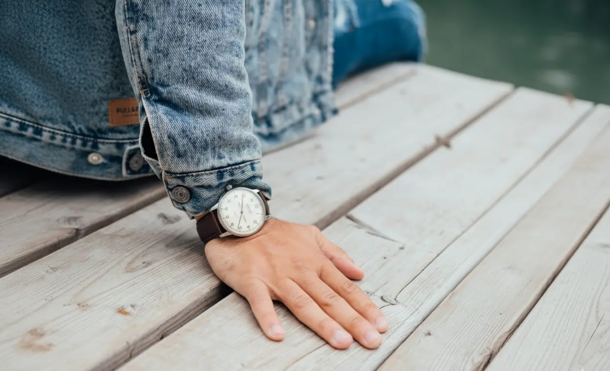 Casual wristwatch on a denim-clad wrist resting on a wooden dock, showcasing versatile everyday styl