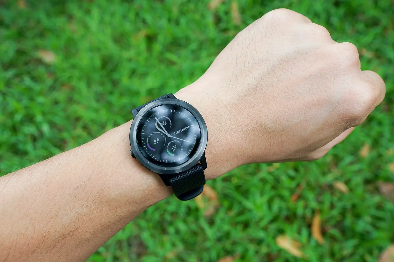 Luxurious black Garmin-style smartwatch on a person’s wrist, set against a green grassy background