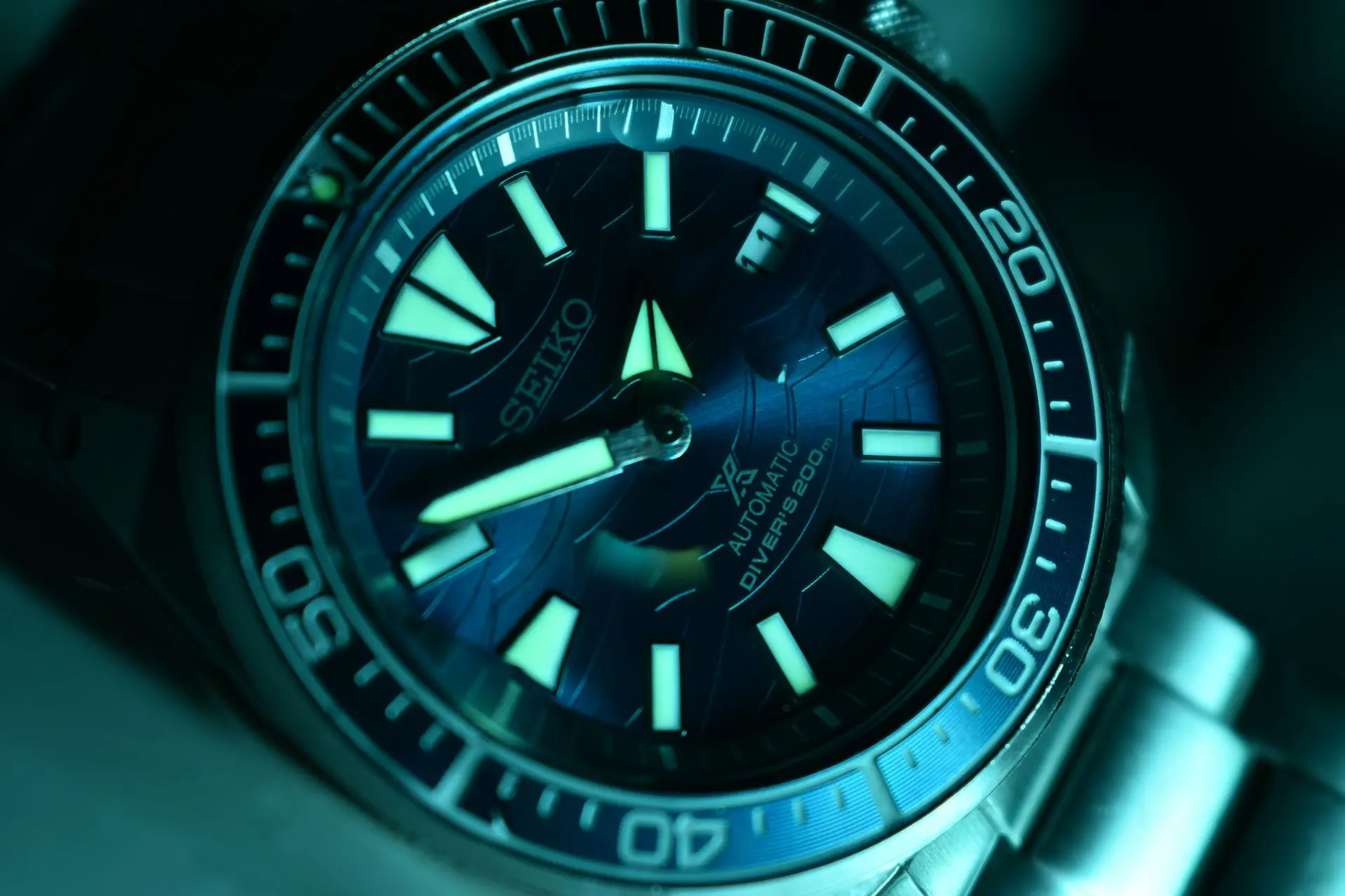 Seiko LumiBrite dive watch showing glowing luminous hands and markers; rotating bezel and stainless steel bracelet.