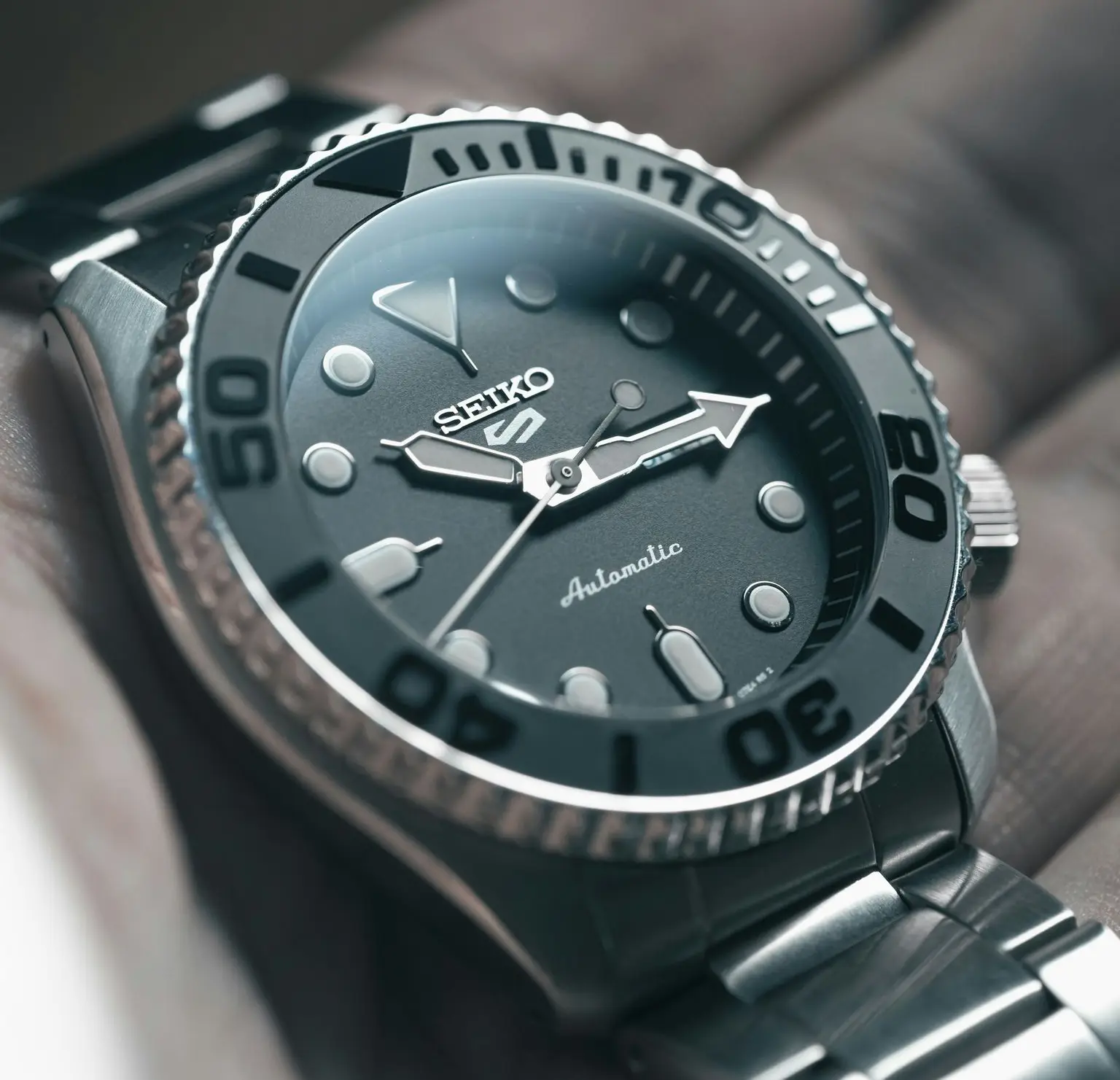 Budget Automatic Diver Watch Close-up of a budget automatic diver's watch with a black dial, large luminous indices, and a stainless steel bezel.