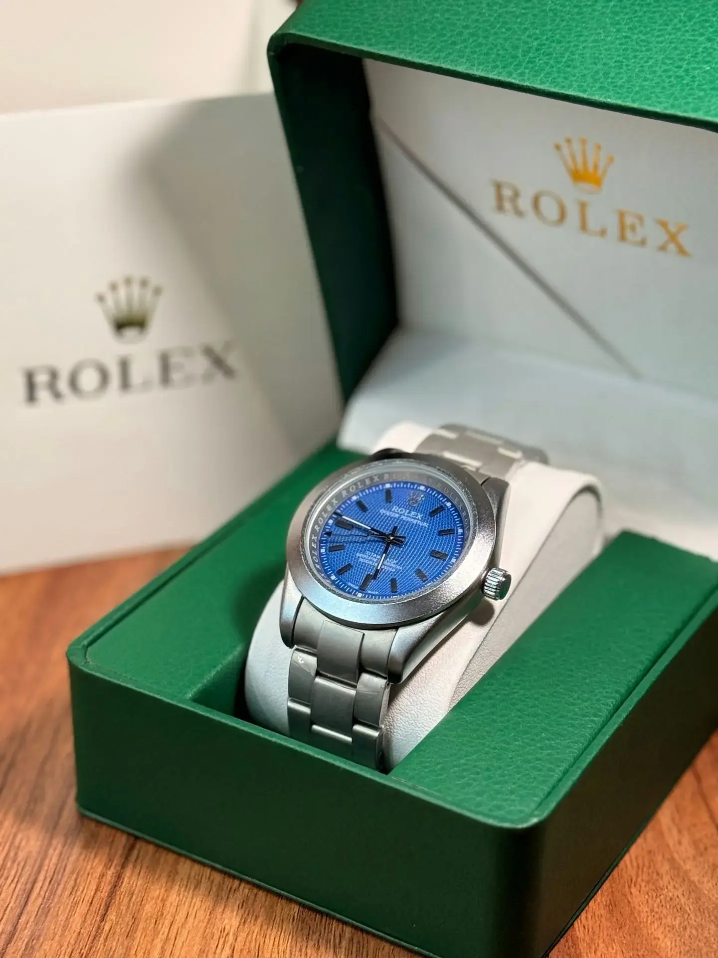 Pre-owned Rolex Luxury Watch with Blue Dial in Green Box Pre-owned Rolex stainless steel watch with a bright blue dial in an open green Rolex presentation box.