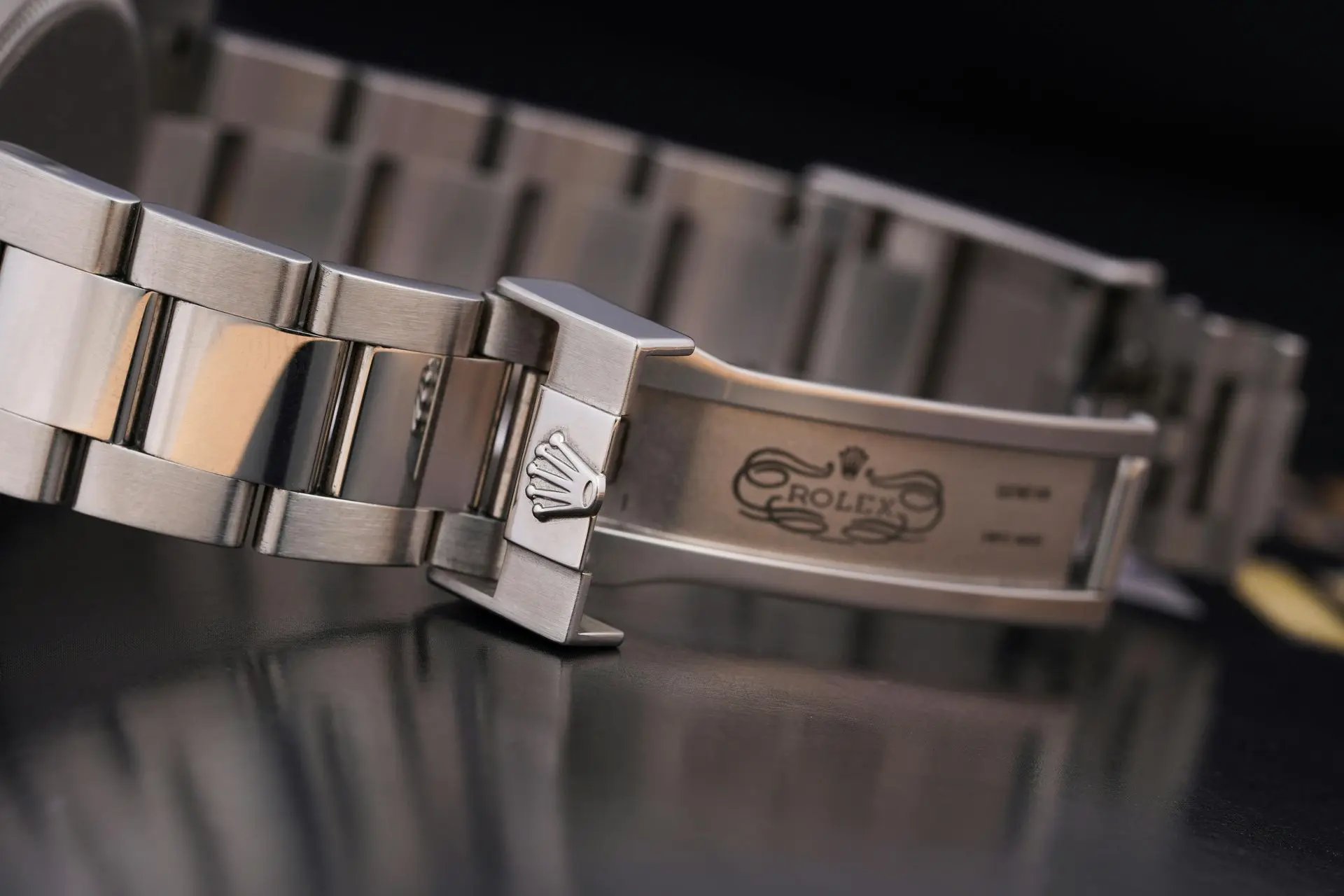 Stainless steel watch strap with folding clasp on a black surface