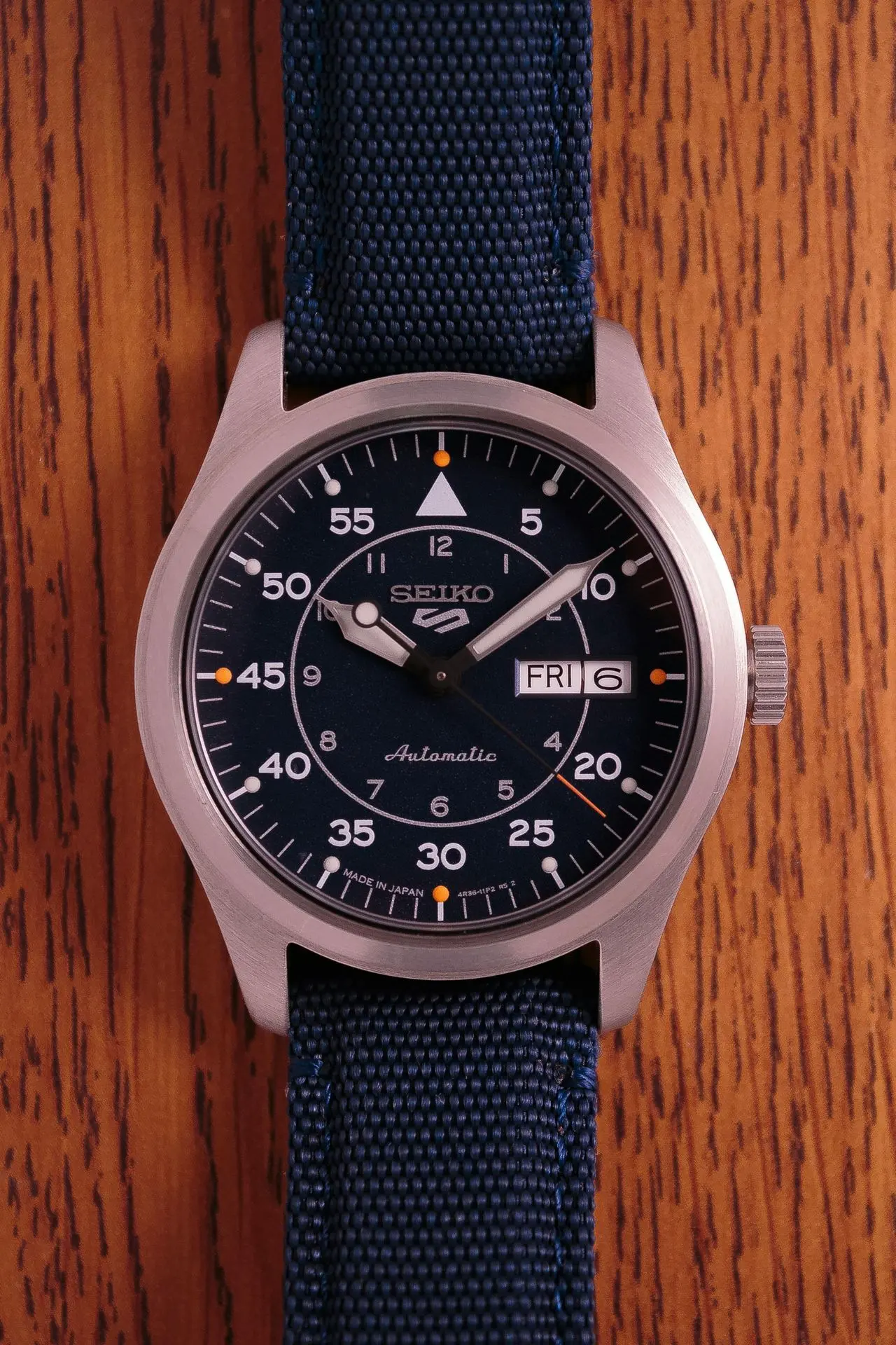 Seiko automatic watch with a blue canvas fabric watch strap on a wooden surface
