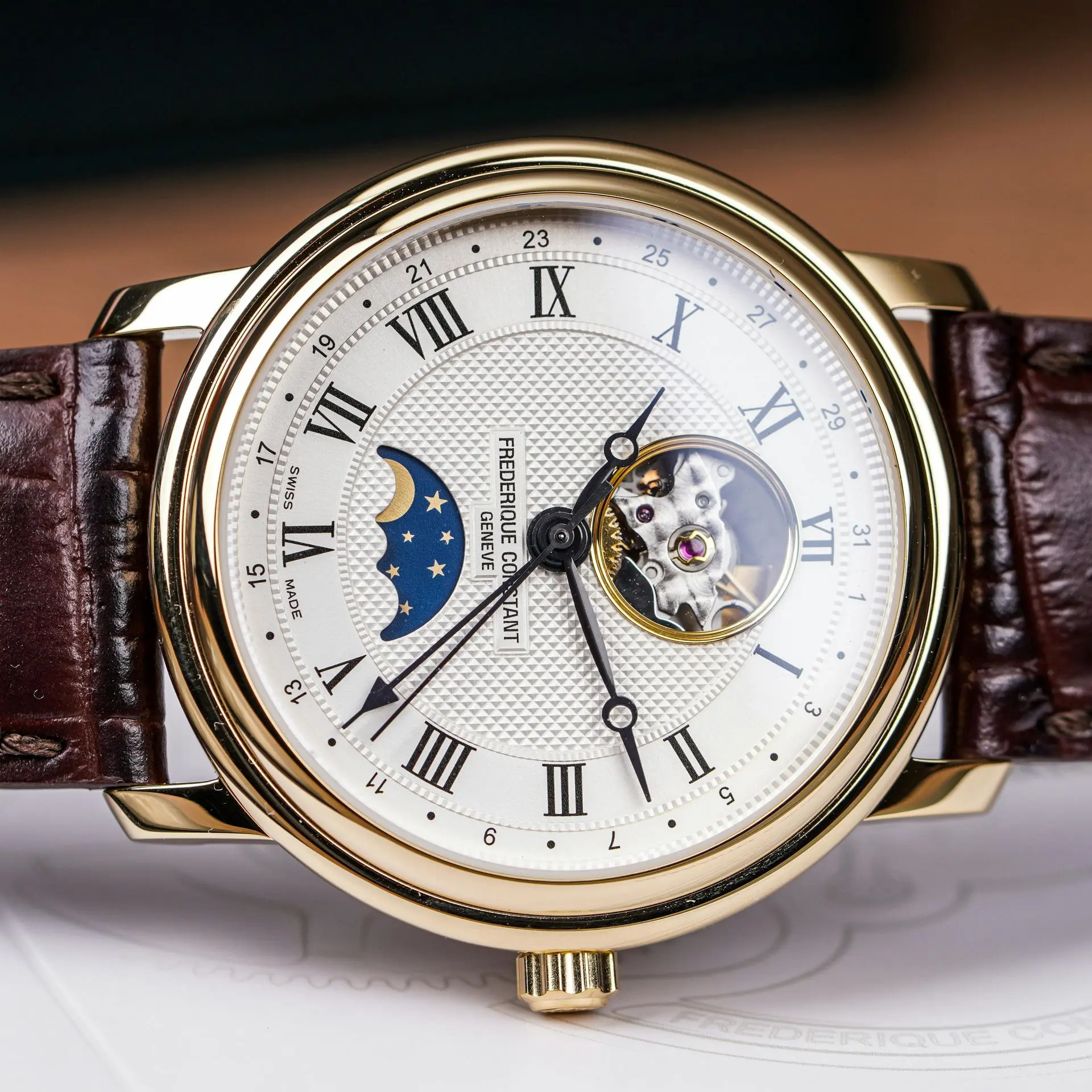 Luxury mechanical wristwatch with moonphase display, open-heart movement, and brown leather strap.