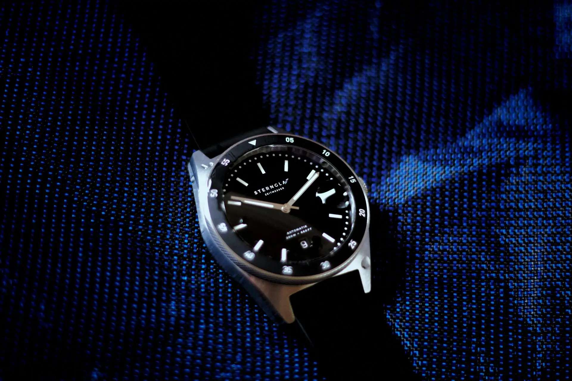 Stylish wristwatch on blue textured fabric background, showcasing composition and creative styling for watch photography