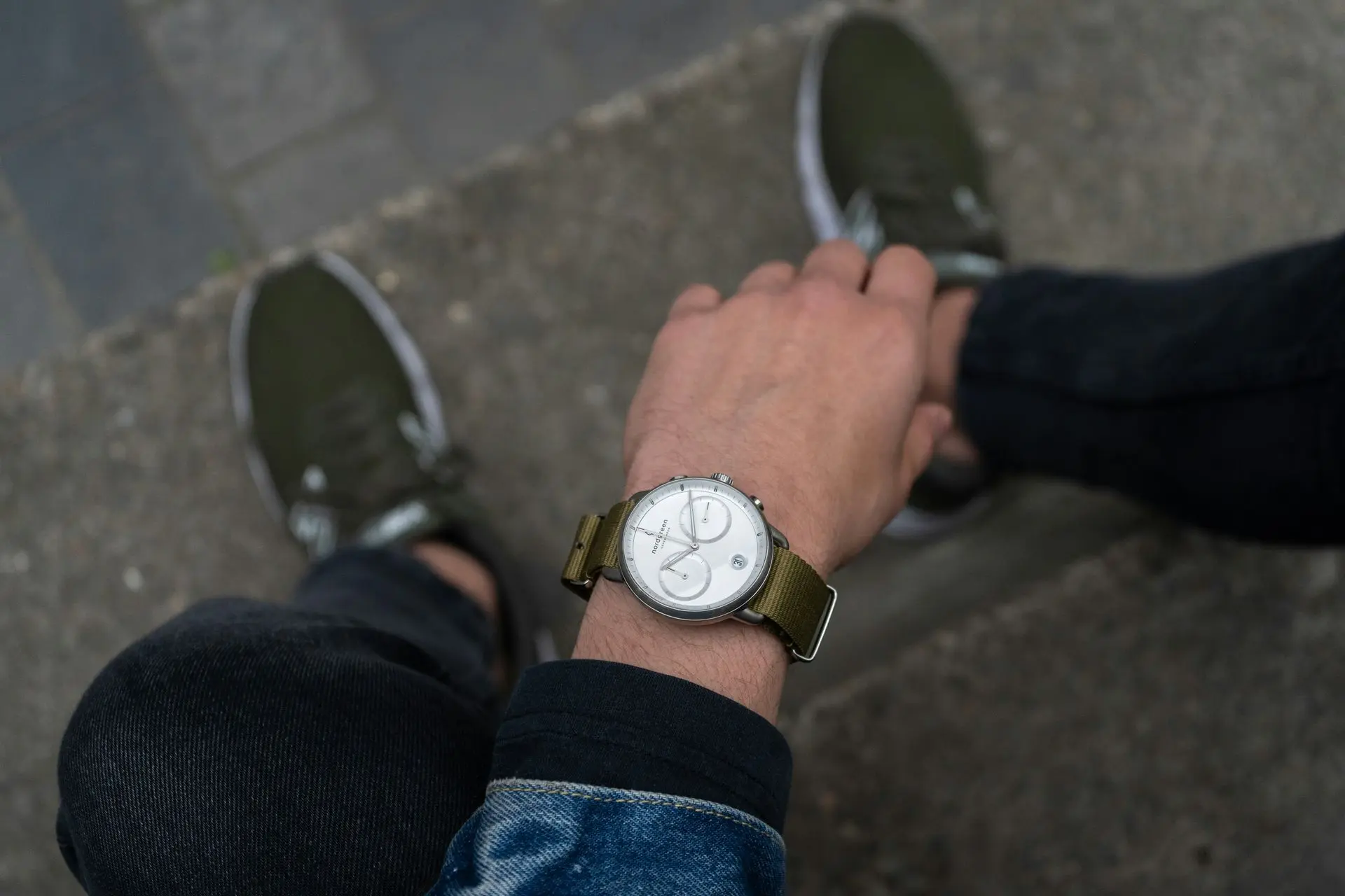 Person wearing an automatic watch while sitting outdoors and tying shoelaces, showing casual afternoon activity.