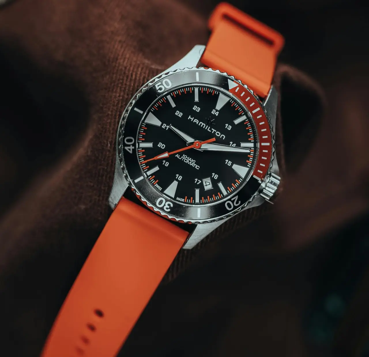 Hamilton Khaki Field Automatic military-style watch with black dial, rotating bezel, and orange strap