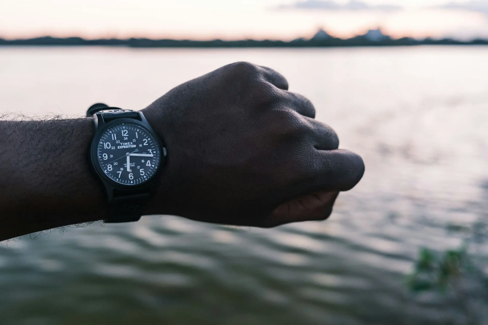 Timex Expedition field watch worn on wrist by the water at sunset