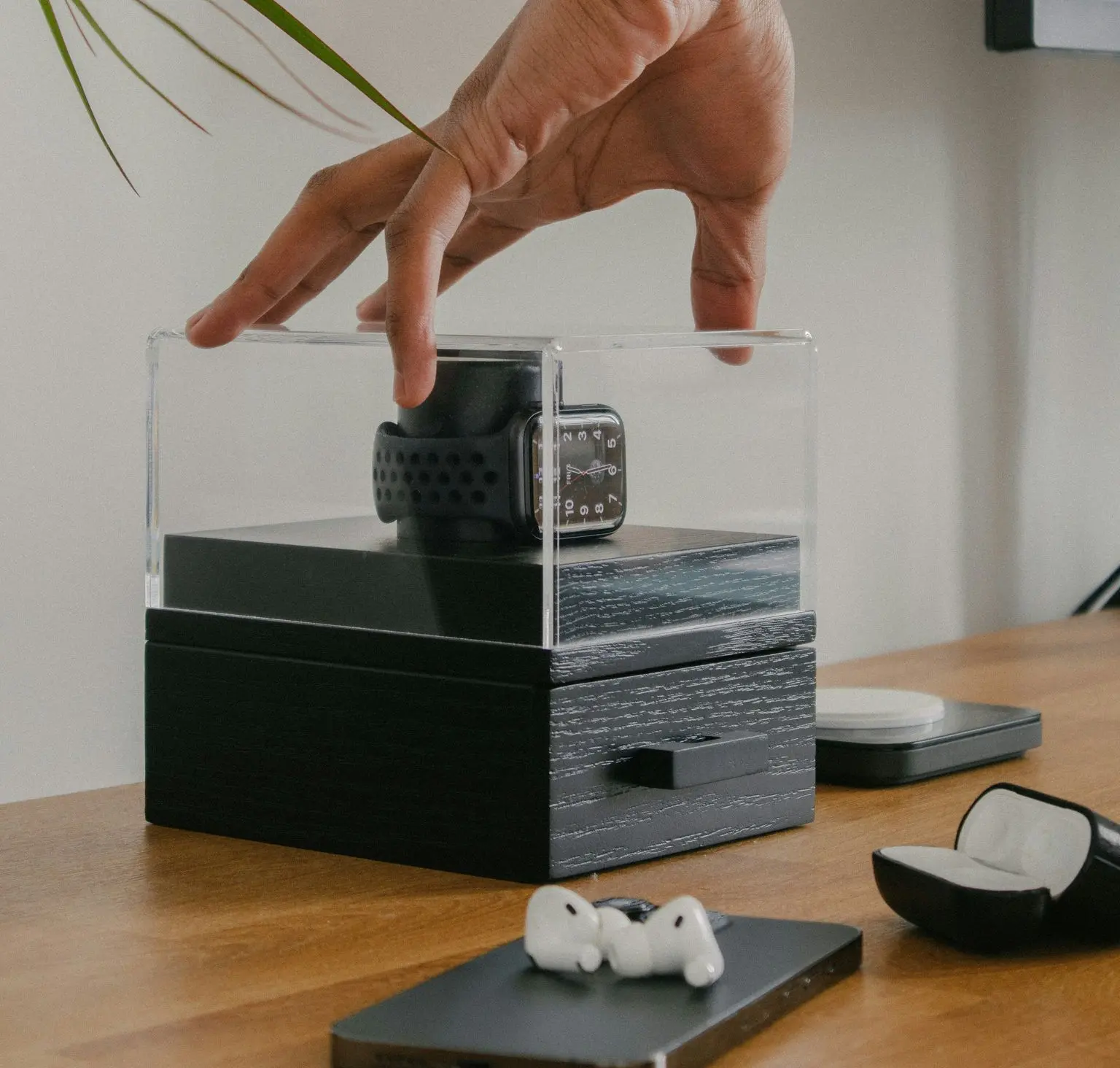 Transparent acrylic watch display box with wooden base and smartwatch inside