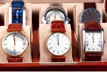 Watch display case with cushioned compartments holding multiple watches with leather straps