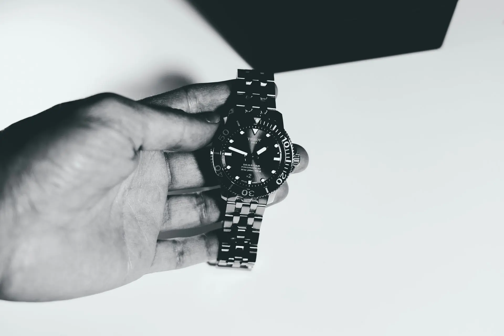 Tissot Seastar 1000 automatic dive watch held in hand with rotating bezel and stainless steel bracelet