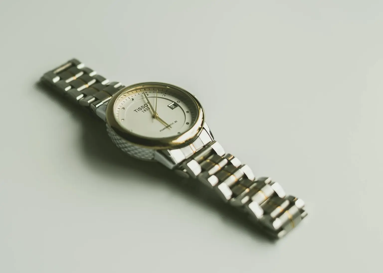 Tissot two-tone watch with gold bezel and stainless steel bracelet on light background