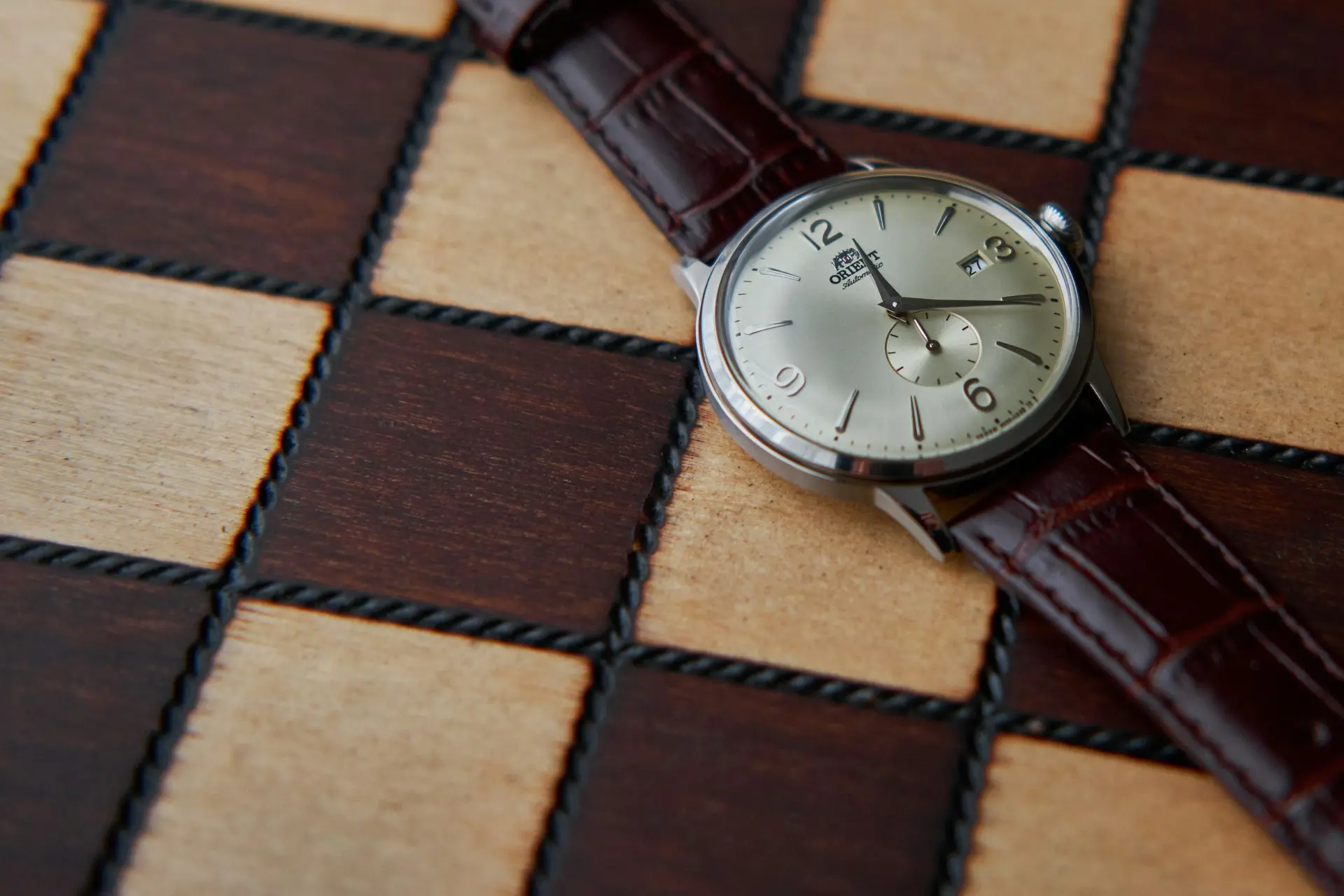 Orient Bambino Small Seconds Classic Dress Watch Orient Bambino Small Seconds dress watch with cream dial and brown leather strap on wooden surface