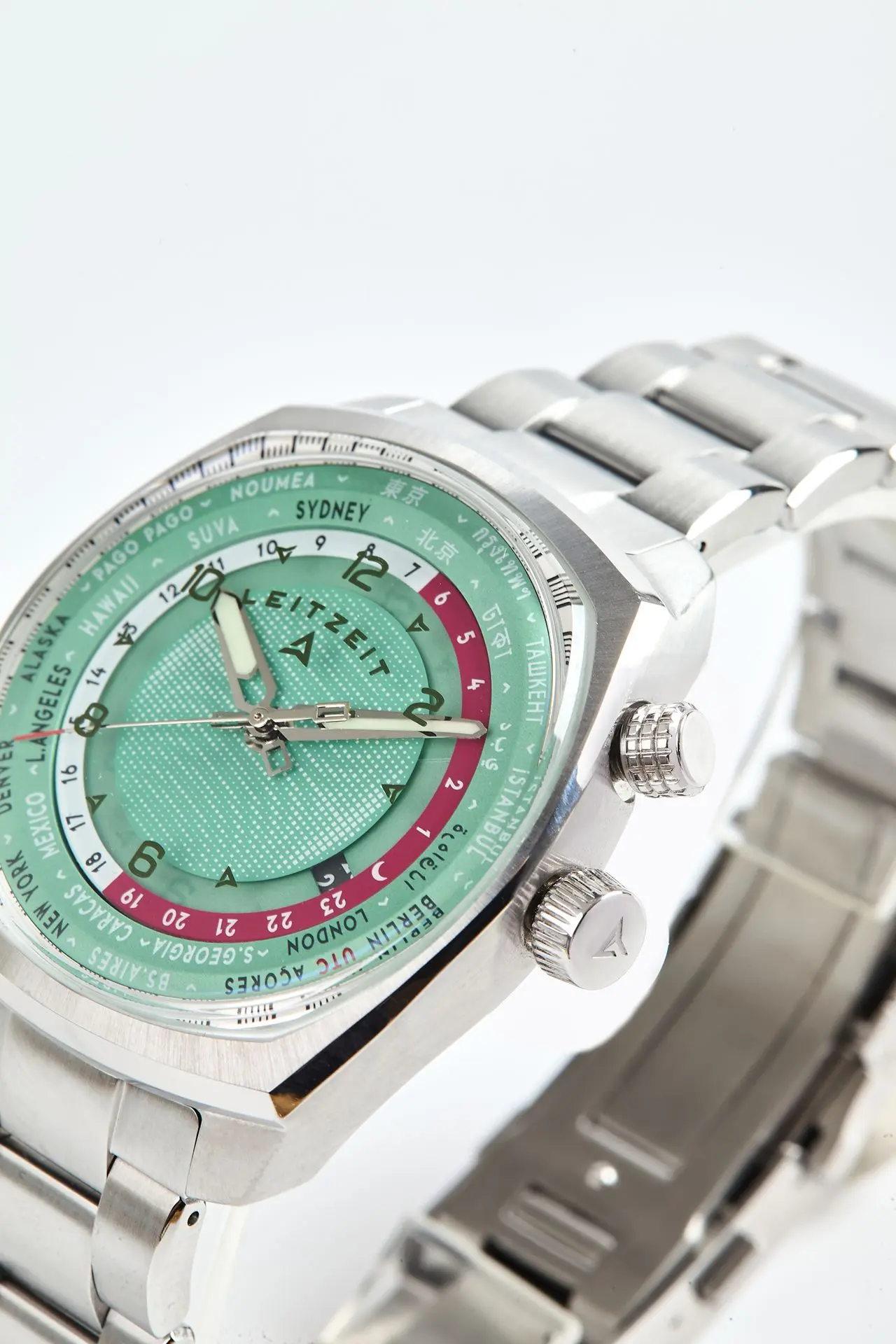 Close-up of the Axis Mundi Worldtimer with green dial, dual crowns and stainless steel bracelet