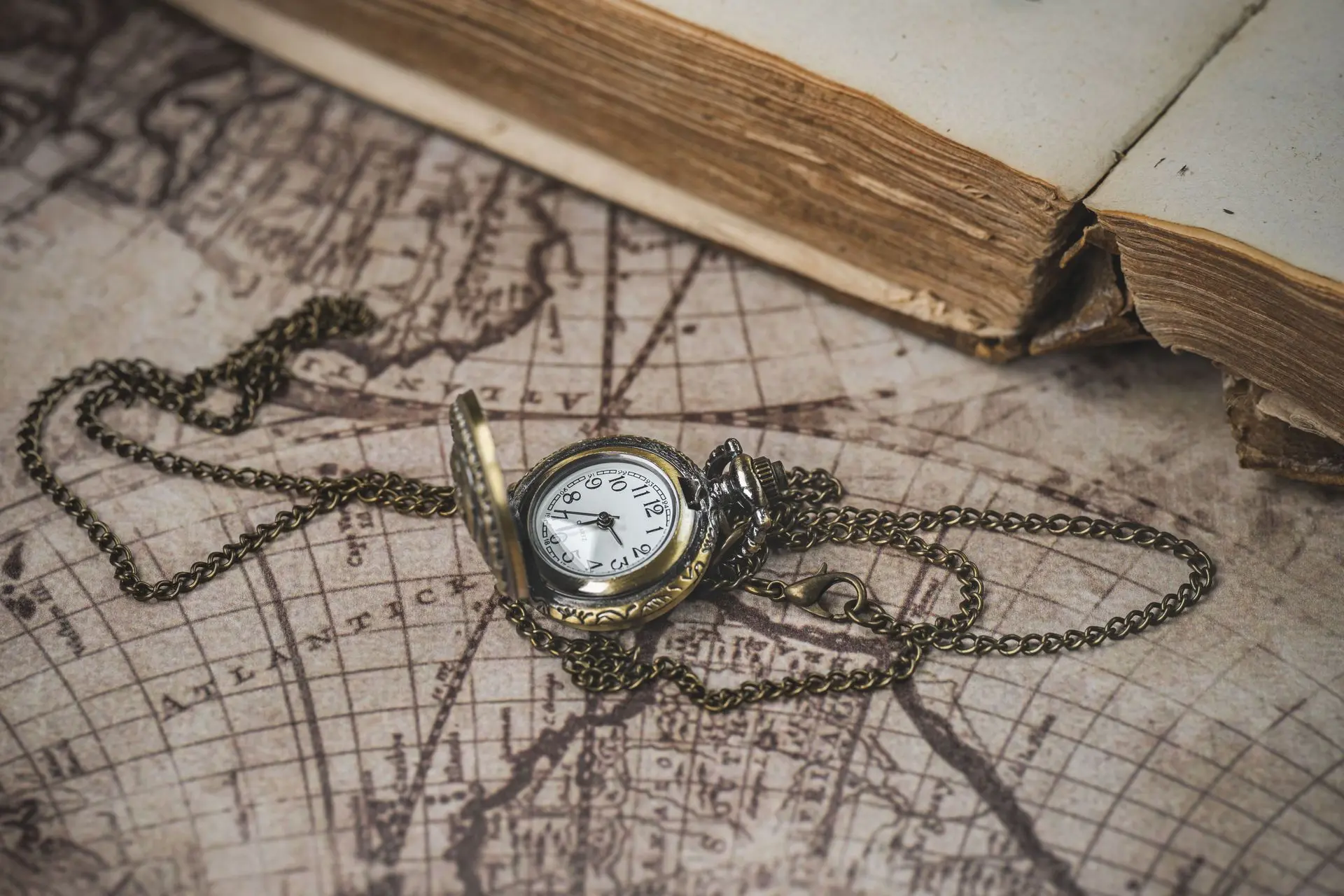 Antique pocket watch with chain on an old map