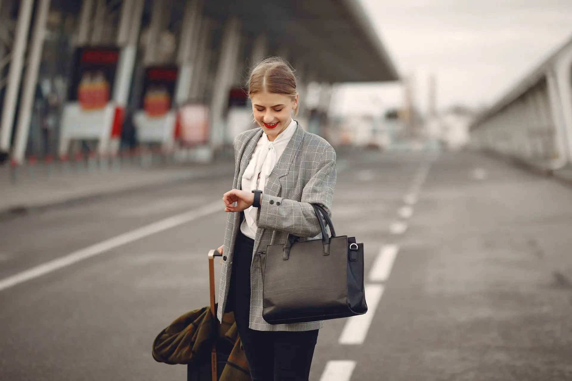Traveller checking her wristwatch at an airport with luggage before departure.