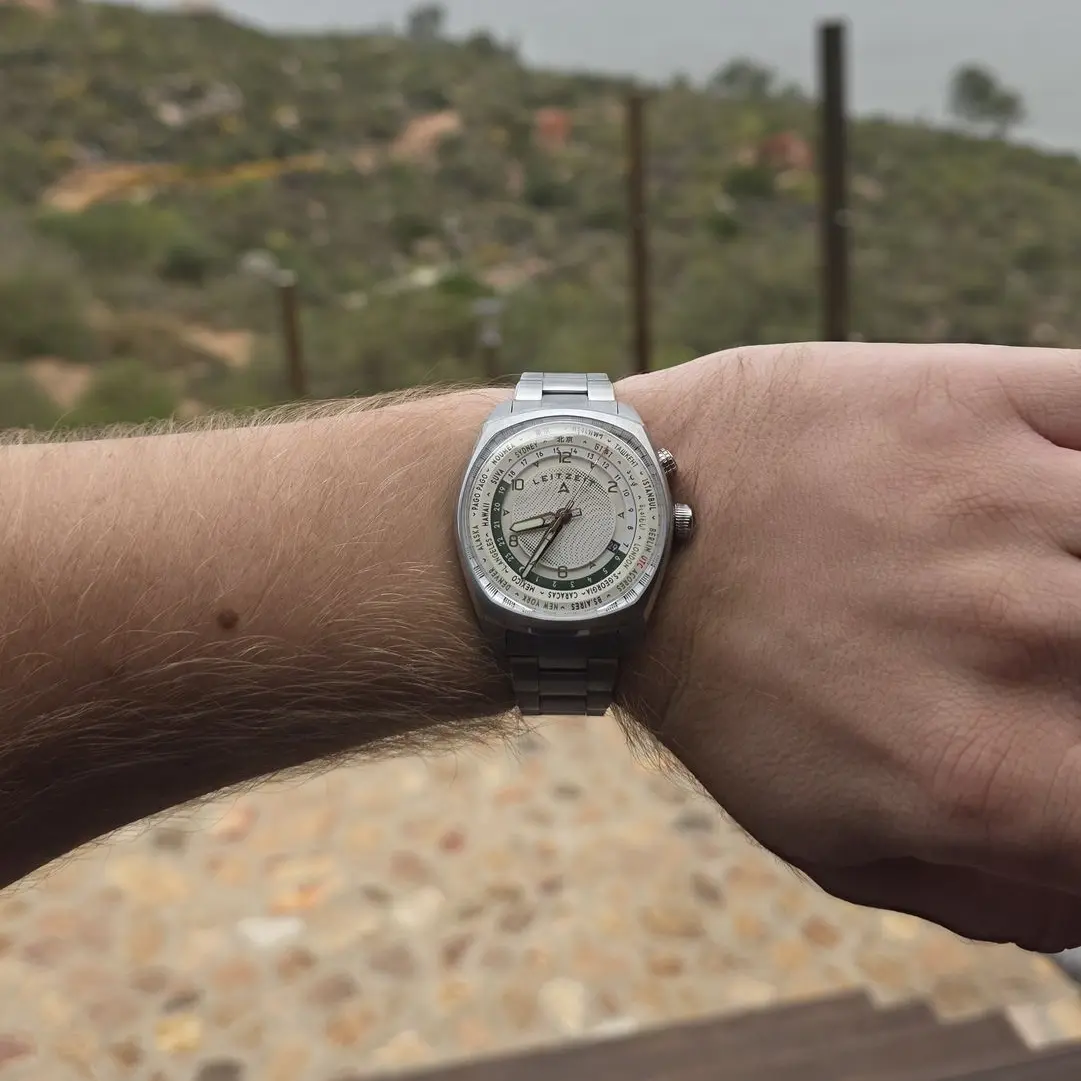 Leitzeit Axis Mundi world timer watch worn on the wrist outdoors, featuring a silver bracelet and multi-city time-zone dial.