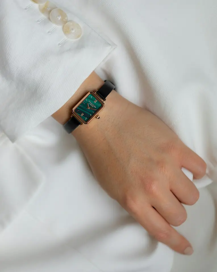 Art Deco-inspired rectangular wristwatch with a green dial and rose gold-tone case styled with a white outfit