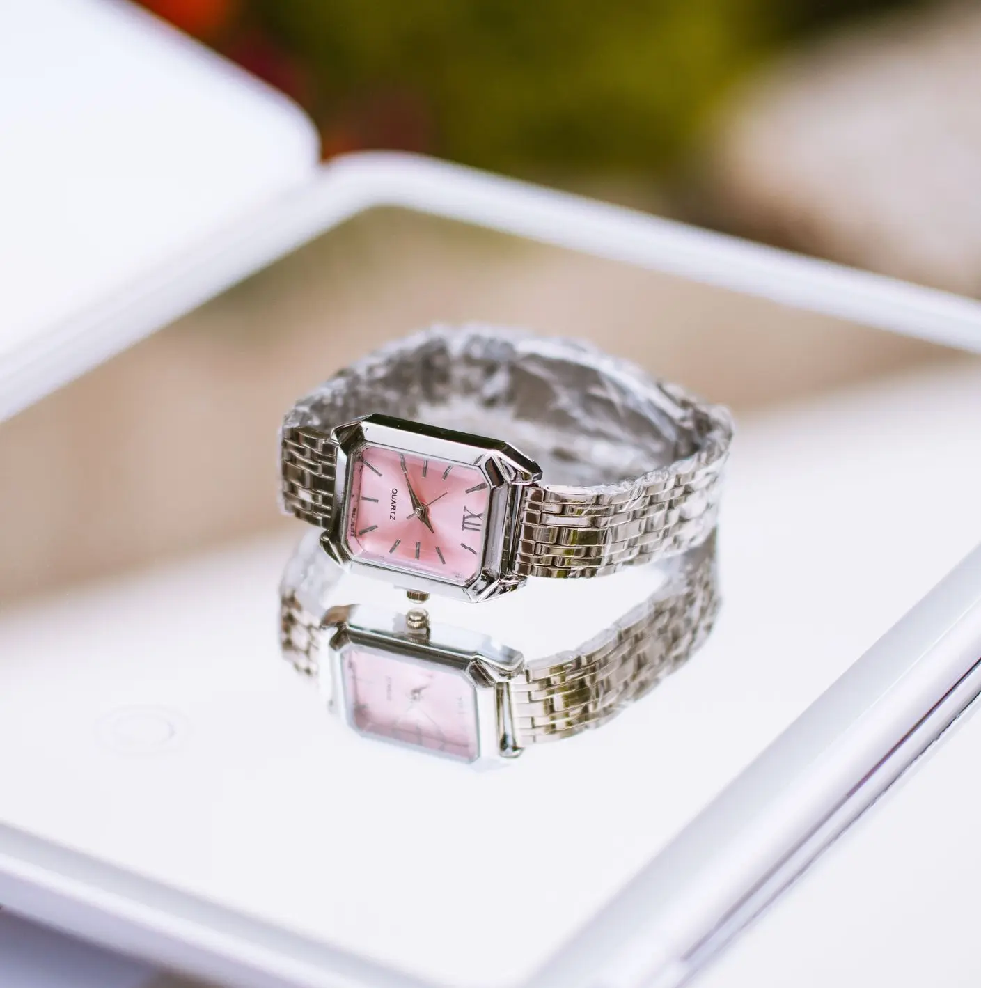 Art Deco Watch Dial with Pink Face and Geometric Details Art Deco-inspired rectangular wristwatch with a pink dial, Roman numerals, and polished silver bracelet